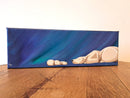 Mini Canvas painting of two polar bears against a blue, starry night sky on a wooden surface.